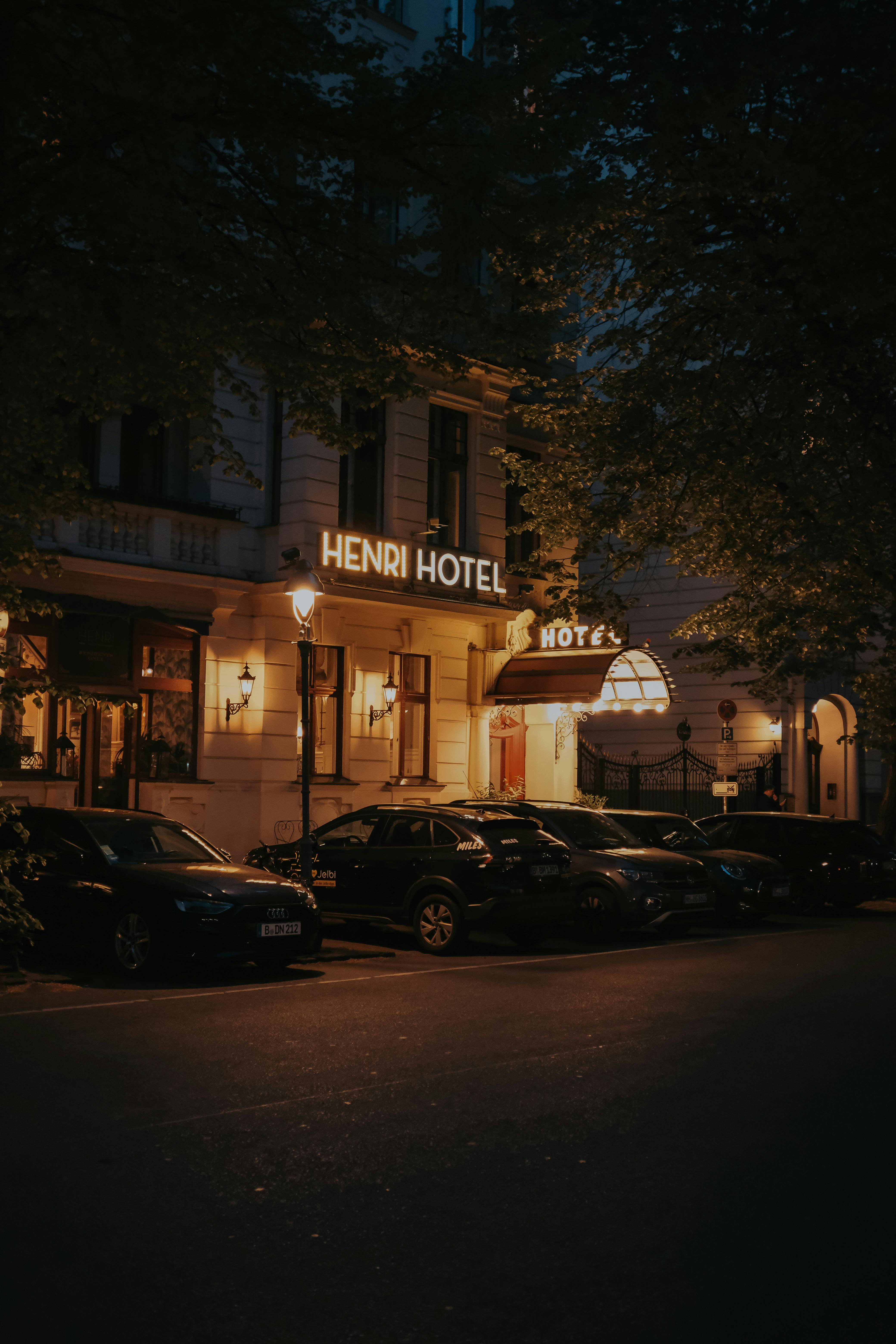 Exterior of Henri Hotel Berlin during night with parked cars and street lights.