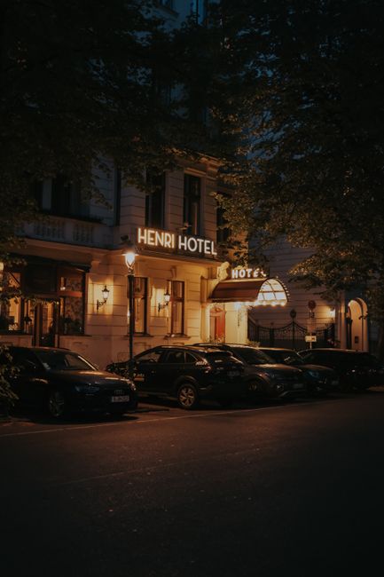 Exterior of Henri Hotel Berlin during night with parked cars and street lights.