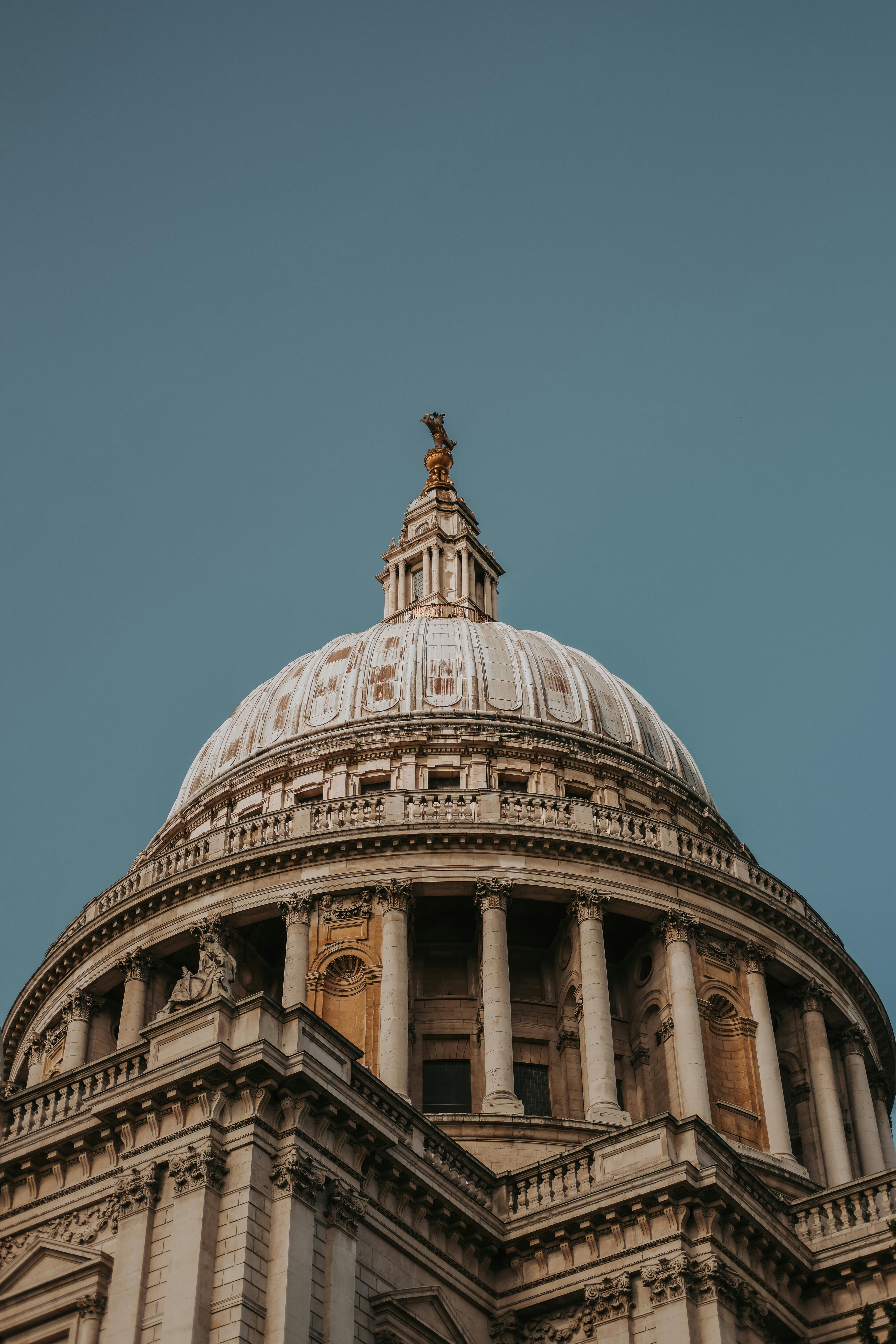 Detailed view of St. Paul's Cathedral dome in London, showcasing architectural grandeur under clear blue sky.