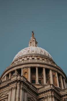 Detailed view of St. Paul's Cathedral dome in London, showcasing architectural grandeur under clear blue sky.