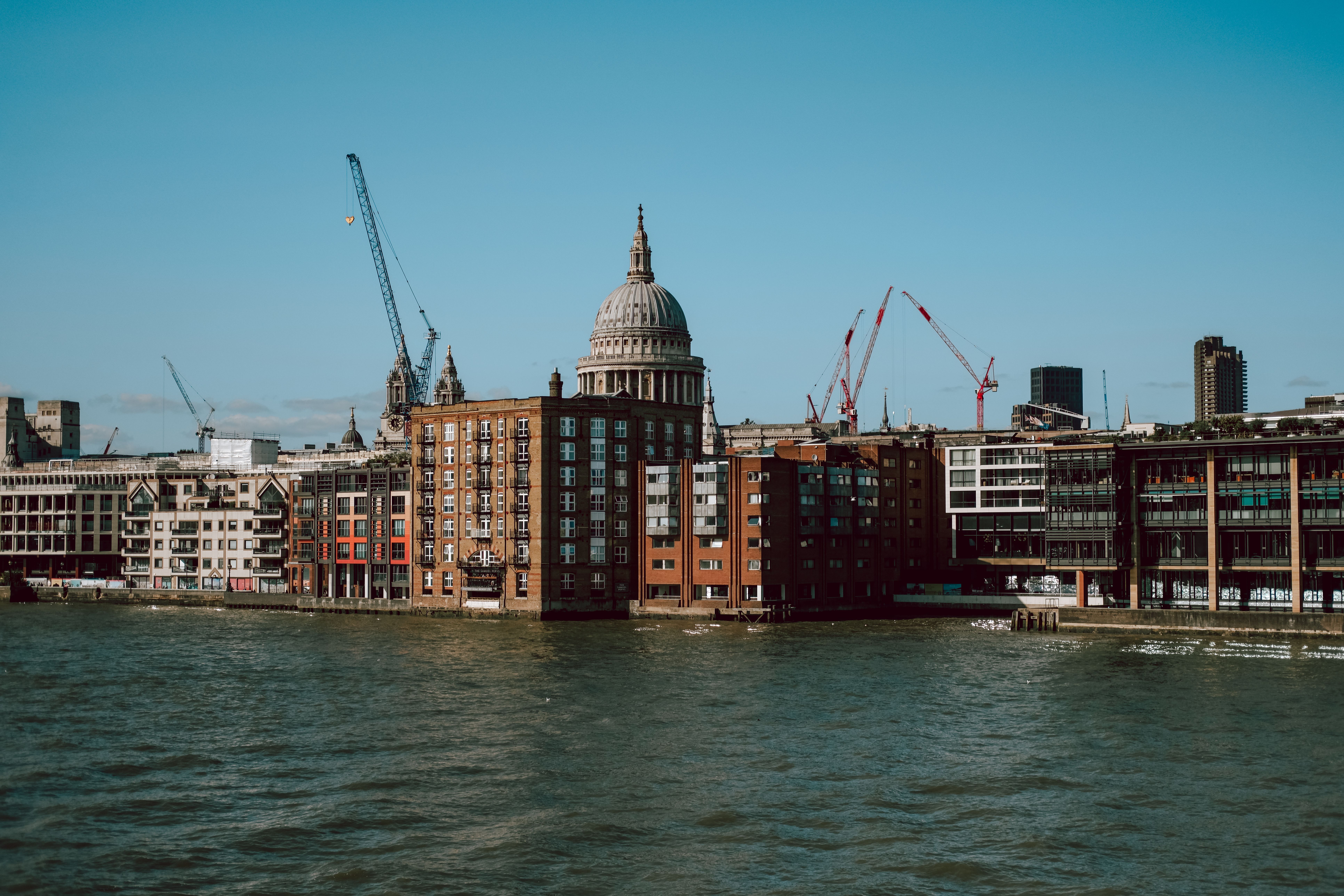 View of St. Paul's Cathedral and riverside buildings under a clear blue sky in London.