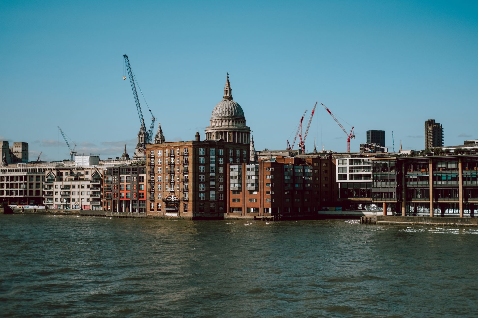 View of St. Paul's Cathedral and riverside buildings under a clear blue sky in London.