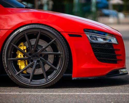 Free Detailed shot of a red luxury sports car's exterior highlighting elegant black wheels and sleek design. Stock Photo