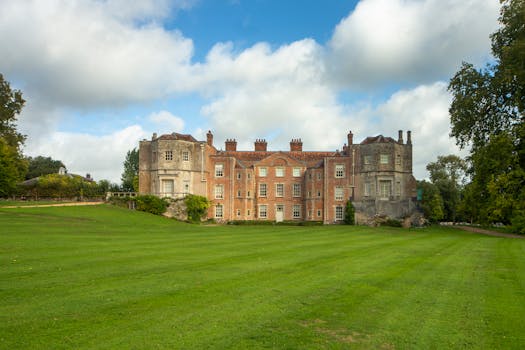 A grand historic mansion set amidst sprawling green lawns under a partly cloudy sky.