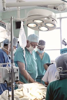 Doctors and nurses work together in a sterile operating room environment to perform a surgery.
