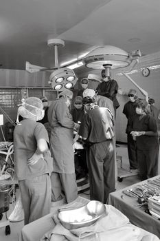 Surgical team performing a medical procedure in a busy operating room. Medical teamwork and precision.
