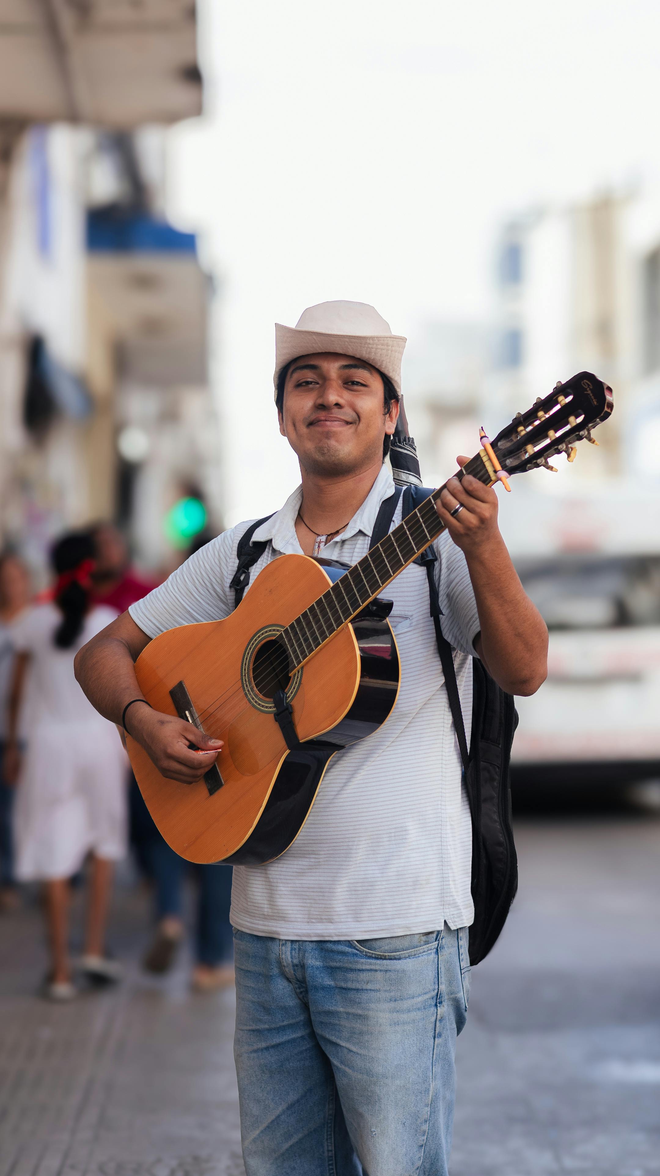 Happy street musician playing acoustic guitar in bustling city street.
