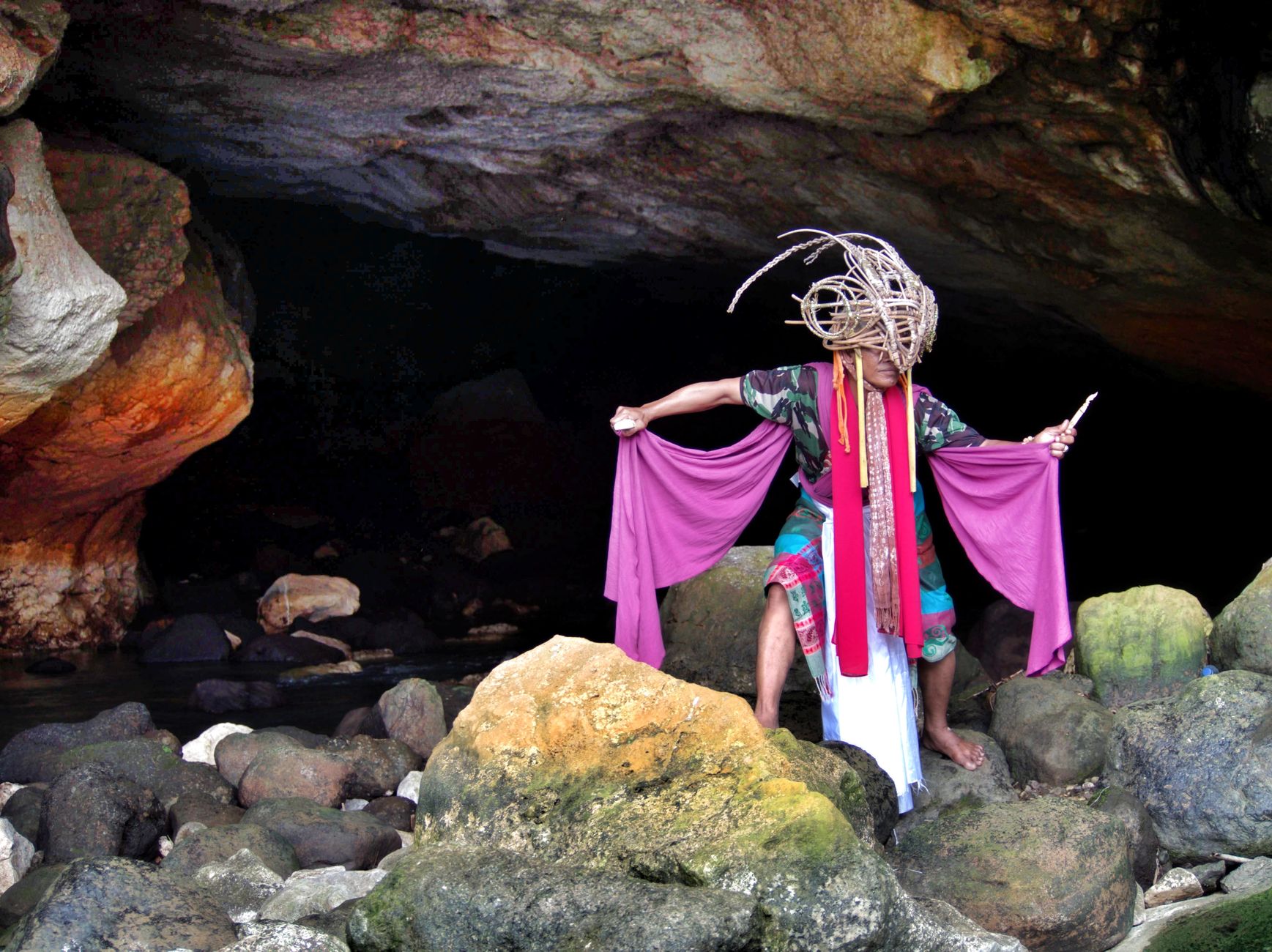 Cultural dance in West Java cave with traditional attire and vibrant cloth.