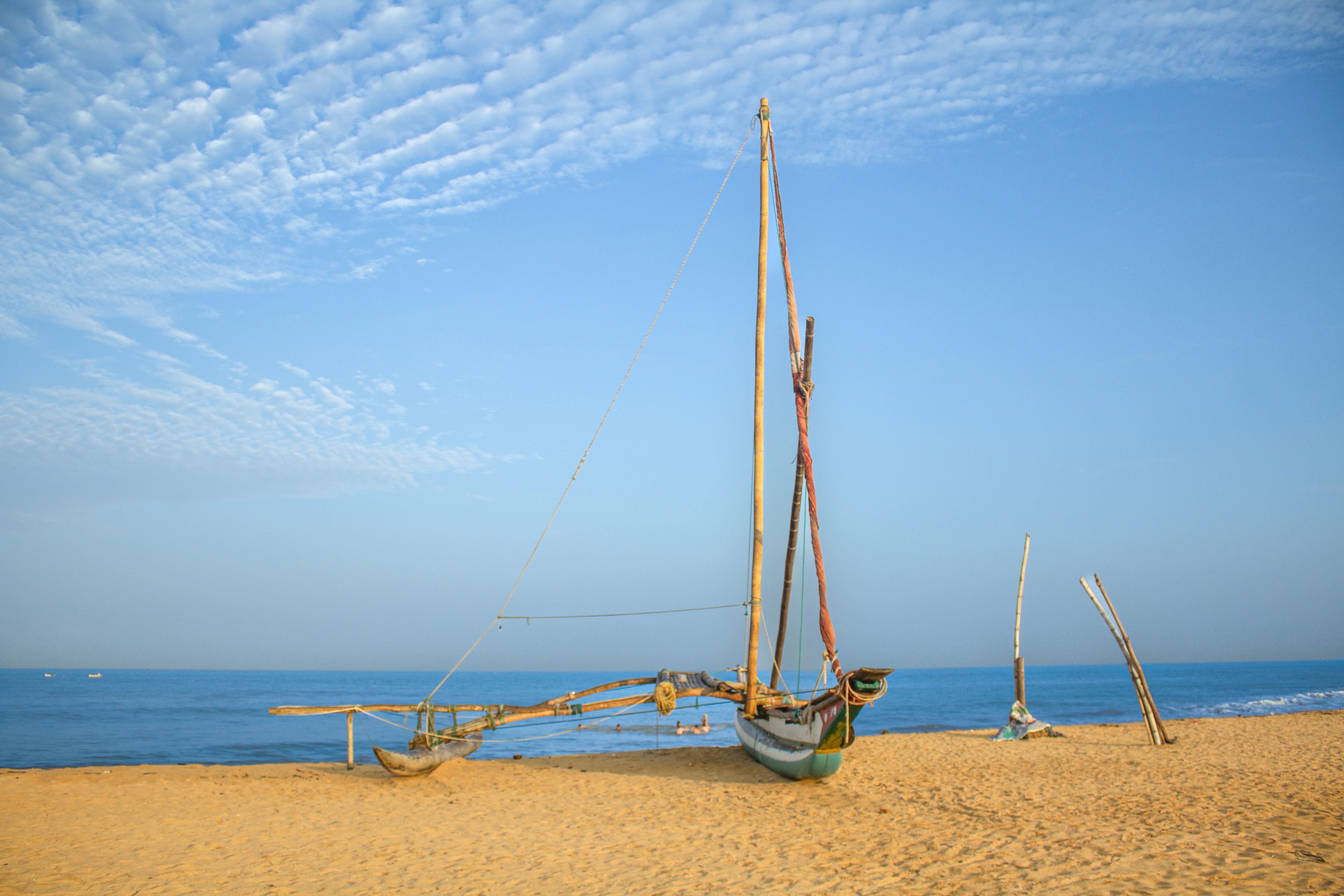 Rustic fishing boats resting on Negombo Beach against a clear blue sky, Sri Lanka's scenic coast.