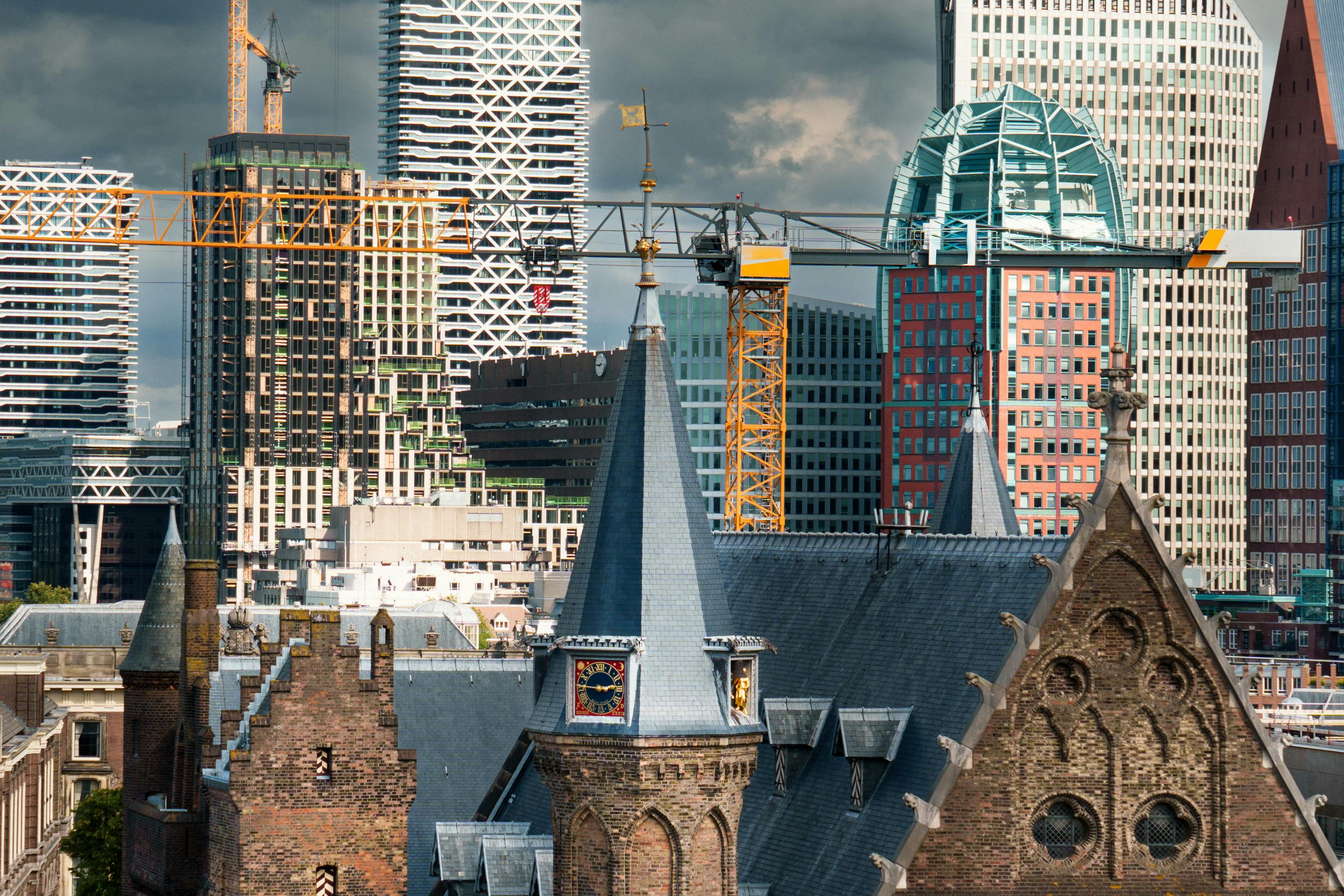The Hague skyline blending historical architecture with modern skyscrapers and cranes.