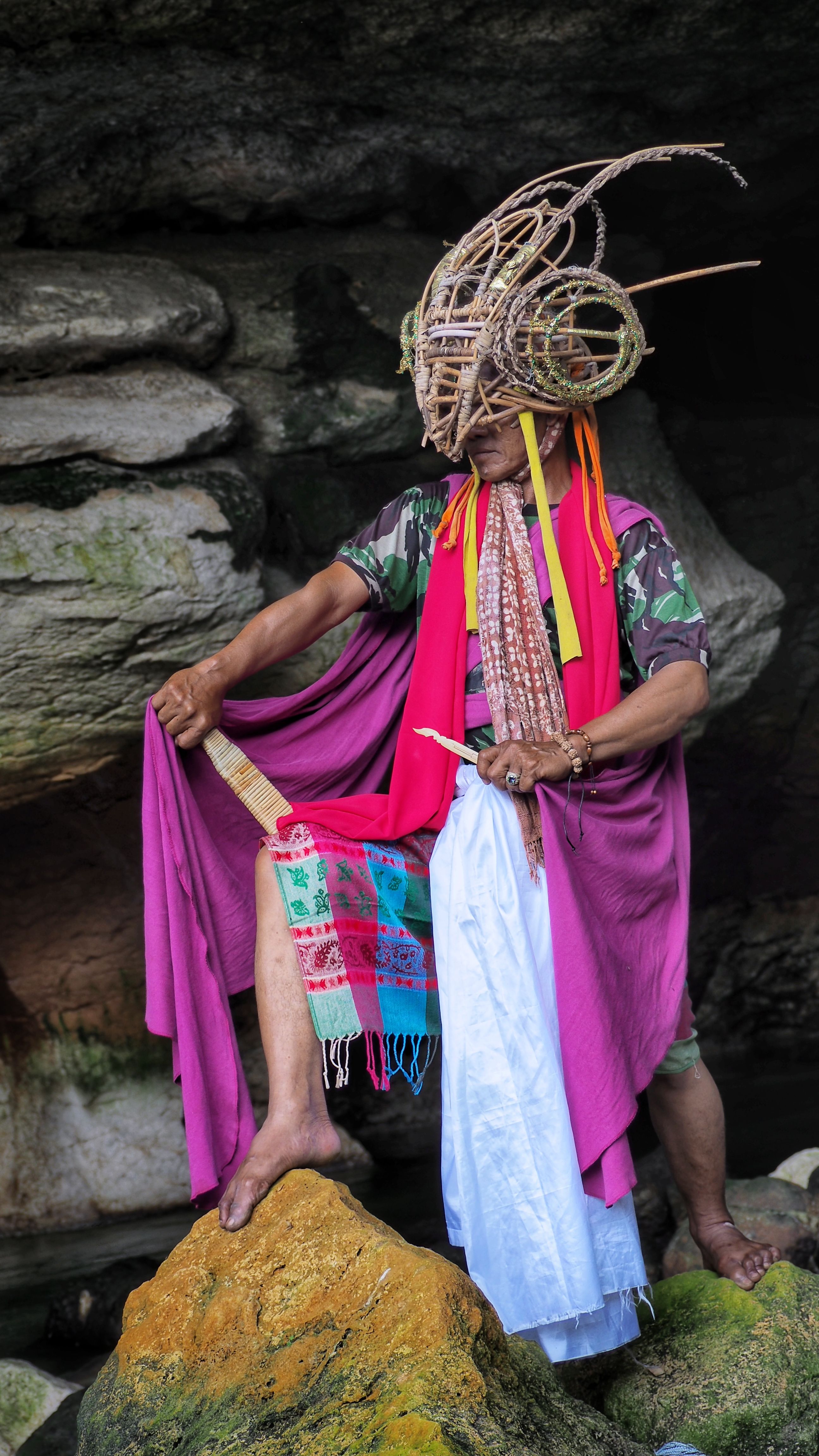 Cultural portrait of a person in traditional attire inside a West Java cave, Indonesia.