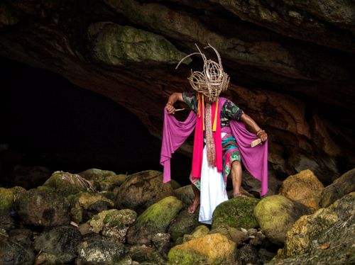 Free A traditional Indonesian dancer performs in a cave, wearing a vibrant, cultural costume. Stock Photo