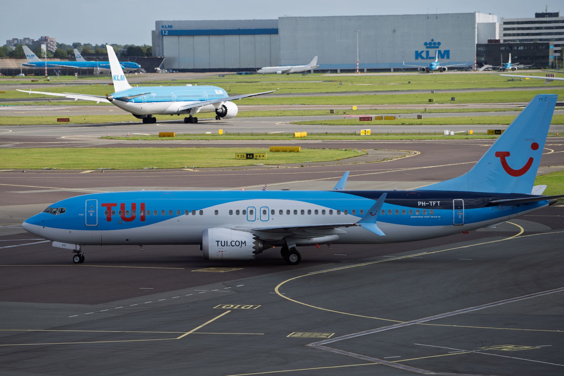 TUI and KLM airplanes on the runway at Schiphol Airport during the day.