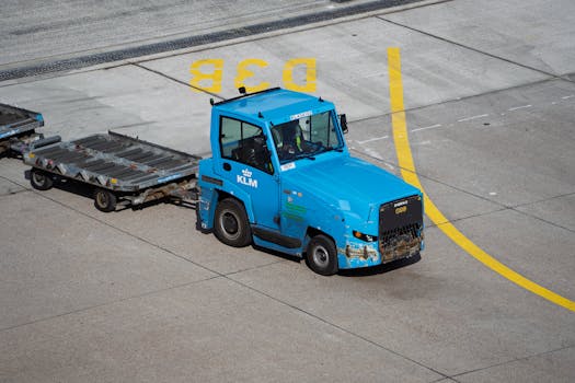 KLM Ground Support Equipment towing baggage carts on airport tarmac.