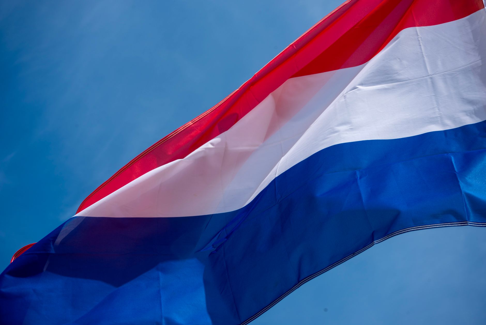 Hollanda'da dil kursunda ders çalışan öğrenciler, masada Hollandaca eğitim materyalleri ve Hollanda bayrağı ile uyum sürecini temsil eden sosyal bir ortam.