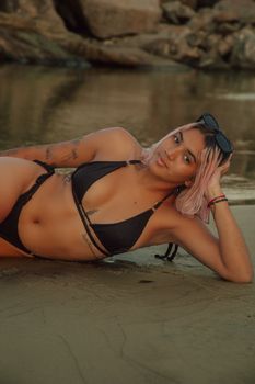 Girl in a bikini lying on the sand, showcasing summer vibes and beach relaxation.