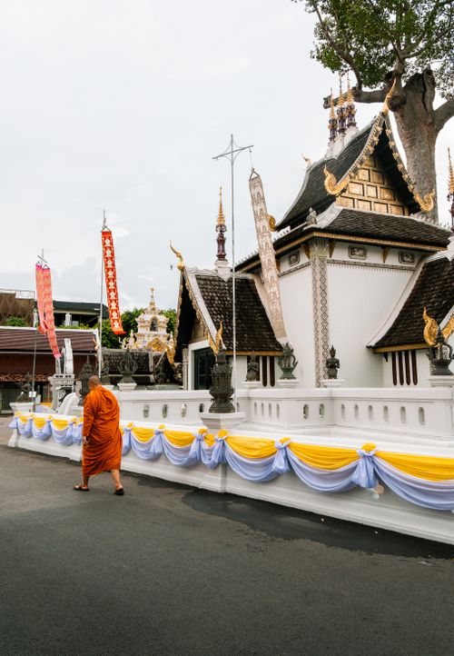 Free A Thai monk in traditional robe walks by a decorated temple in Chiang Mai, Thailand. Stock Photo