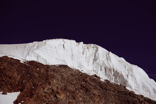 Stunning view of a snow-covered glacier in Saas-Fee, Wallis, Switzerland, under a vibrant sky.
