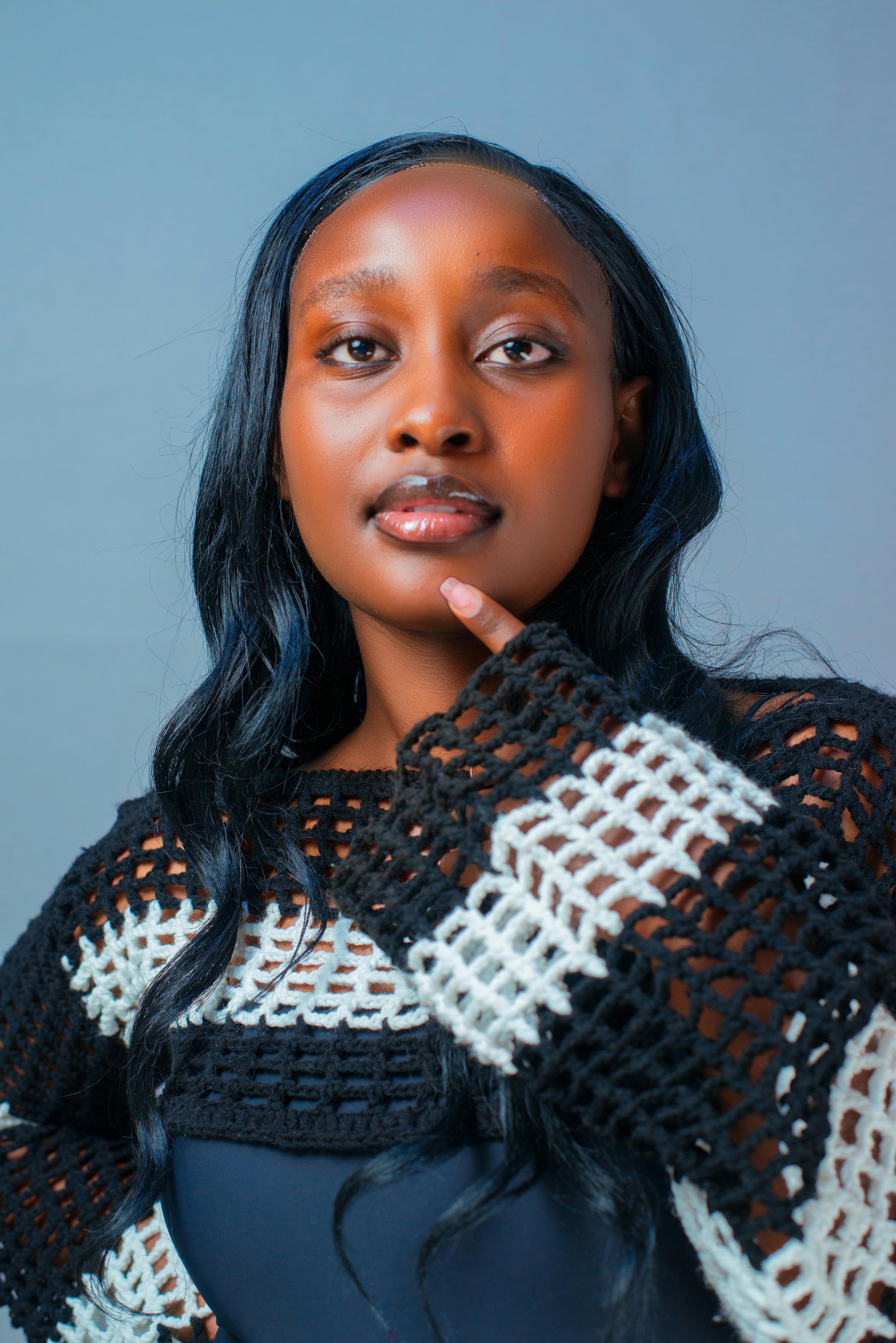 A young woman in a stylish sweater poses confidently with a thoughtful expression.