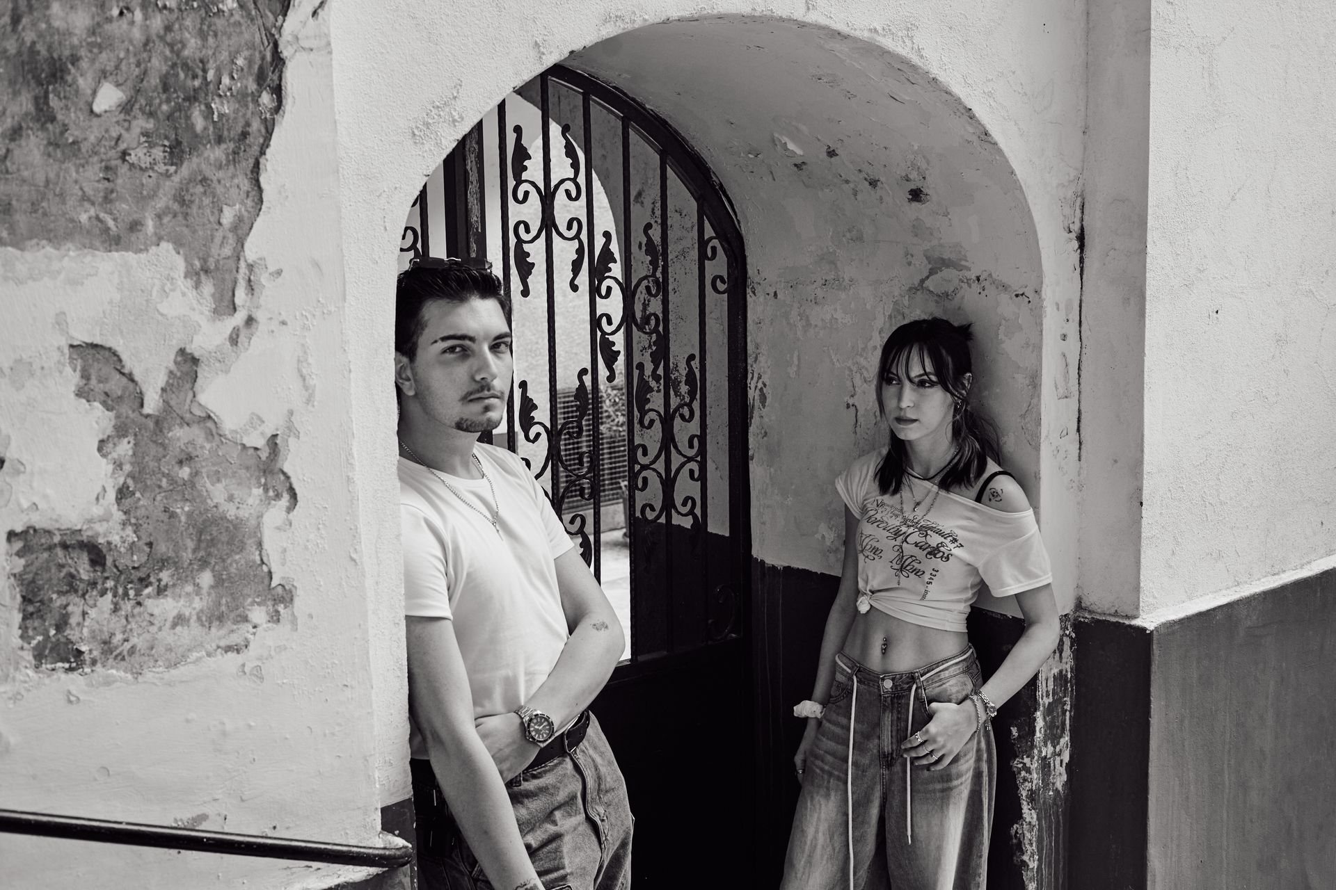 Black and white portrait of two stylish adults leaning against an archway in Istanbul.