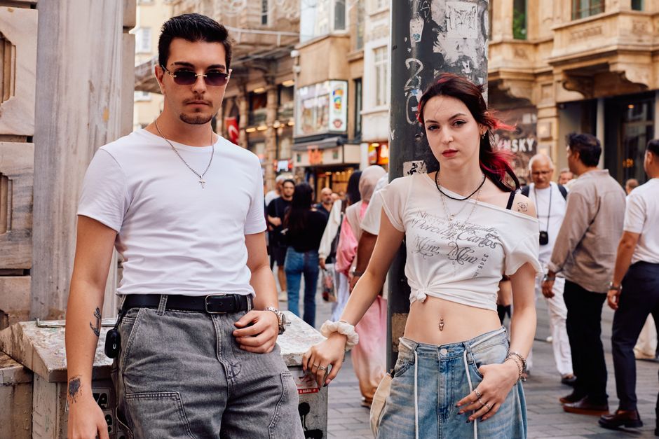 Young adults pose stylishly on a bustling street in Istanbul, highlighting casual urban fashion.