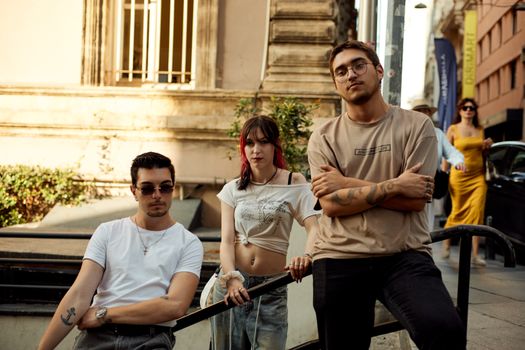 Three stylish young adults pose confidently on a street in İstanbul, showcasing urban fashion.
