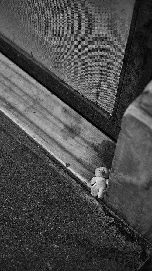 Free A monochrome image of a teddy bear left on a street corner, conveying solitude and nostalgia. Stock Photo