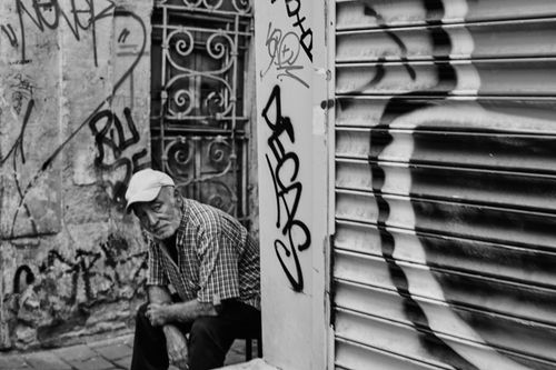 Free Black and white photo of a senior man sitting in an alley with graffiti walls in Istanbul. Stock Photo
