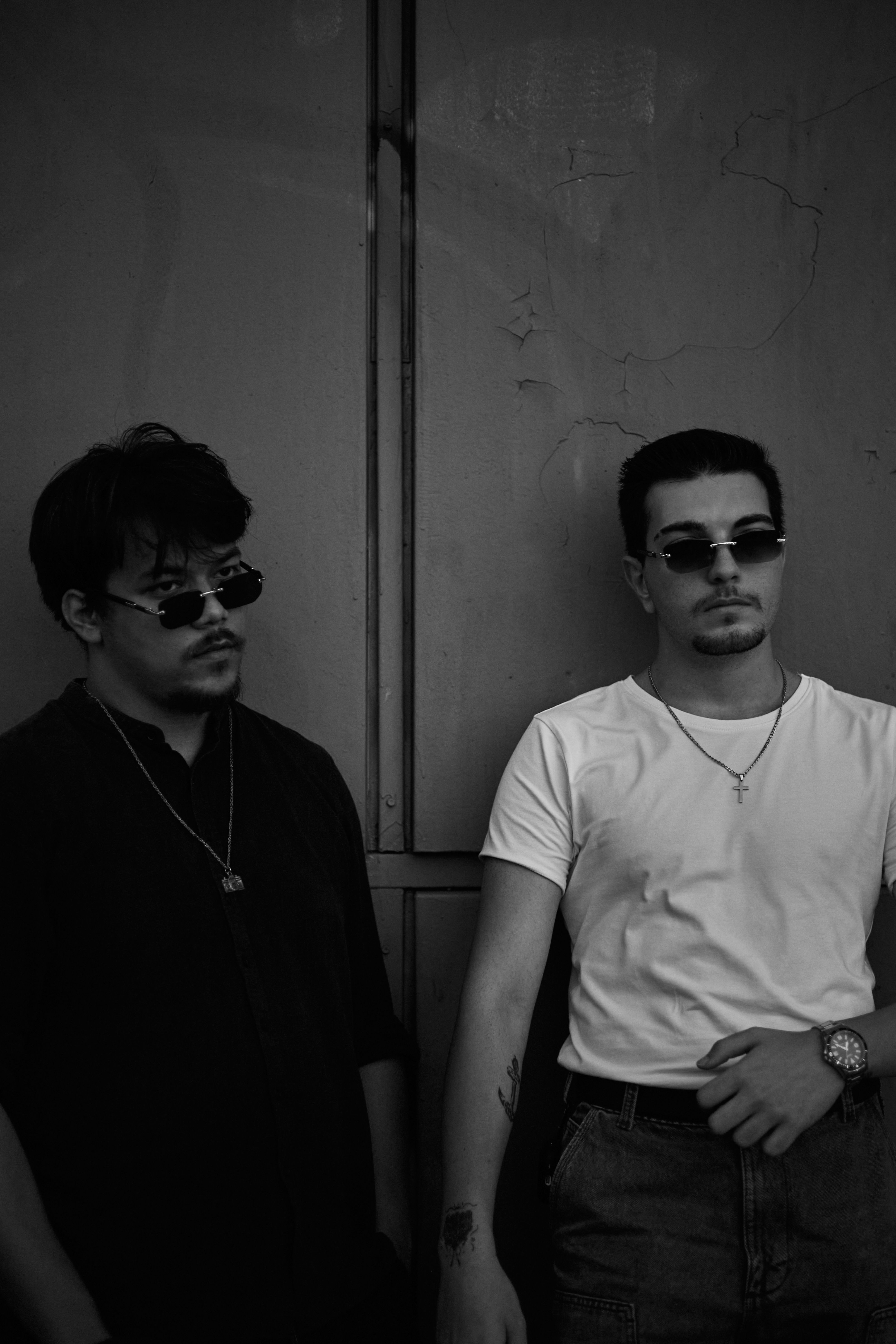 Black and white portrait of two young men wearing sunglasses, exuding a moody and contemplative vibe.