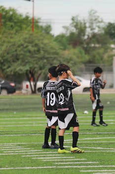 Children playing a soccer game on a green field during the day.