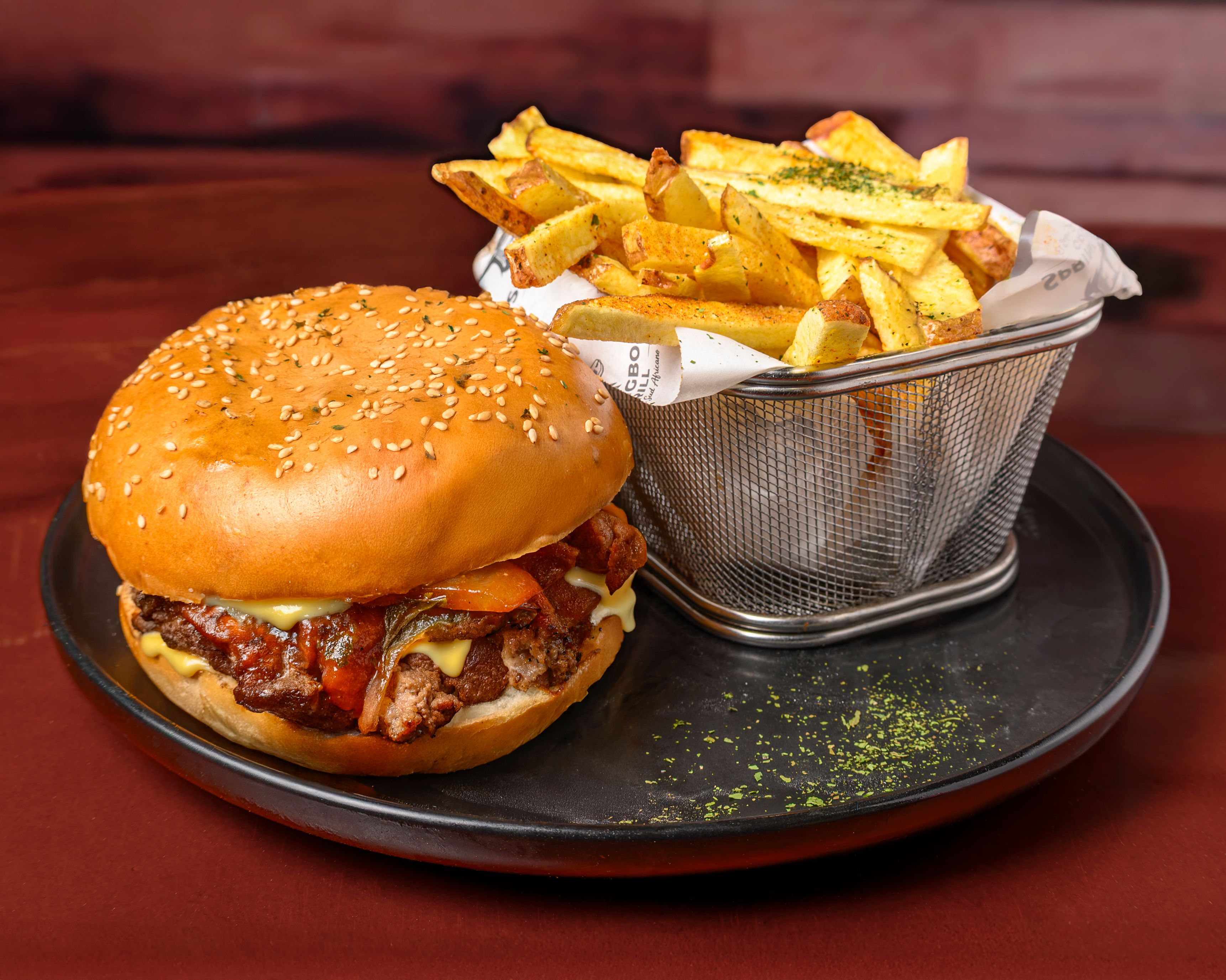 Delicious cheeseburger with crispy fries in a metal basket on a black plate. Perfect food photography.