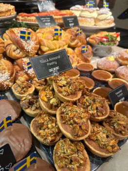Assorted Swedish pastries with flags in a bakery setting, featuring Tosca almond and cinnamon rolls.