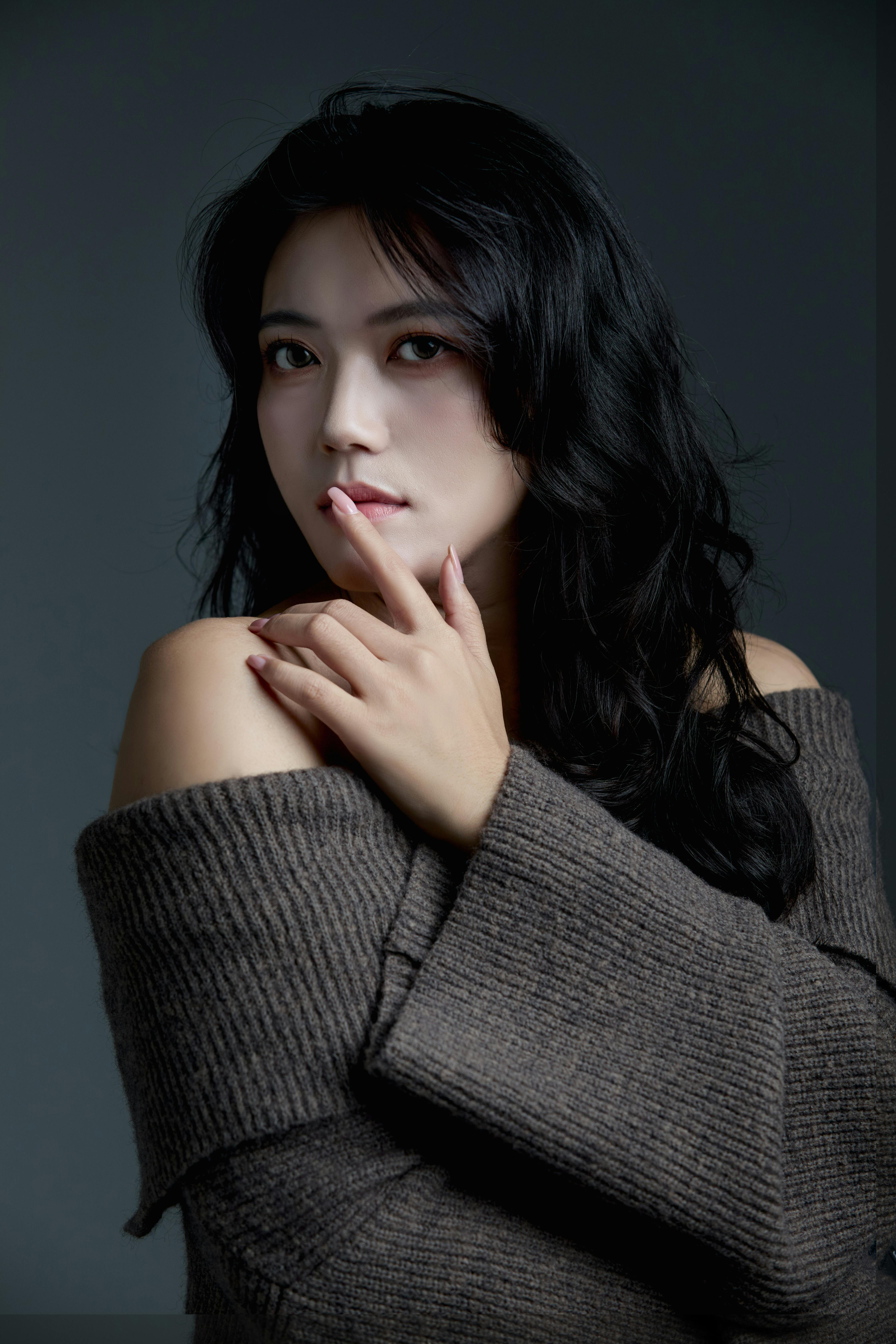 Elegant portrait of a woman with dark hair in a cozy sweater indoors.
