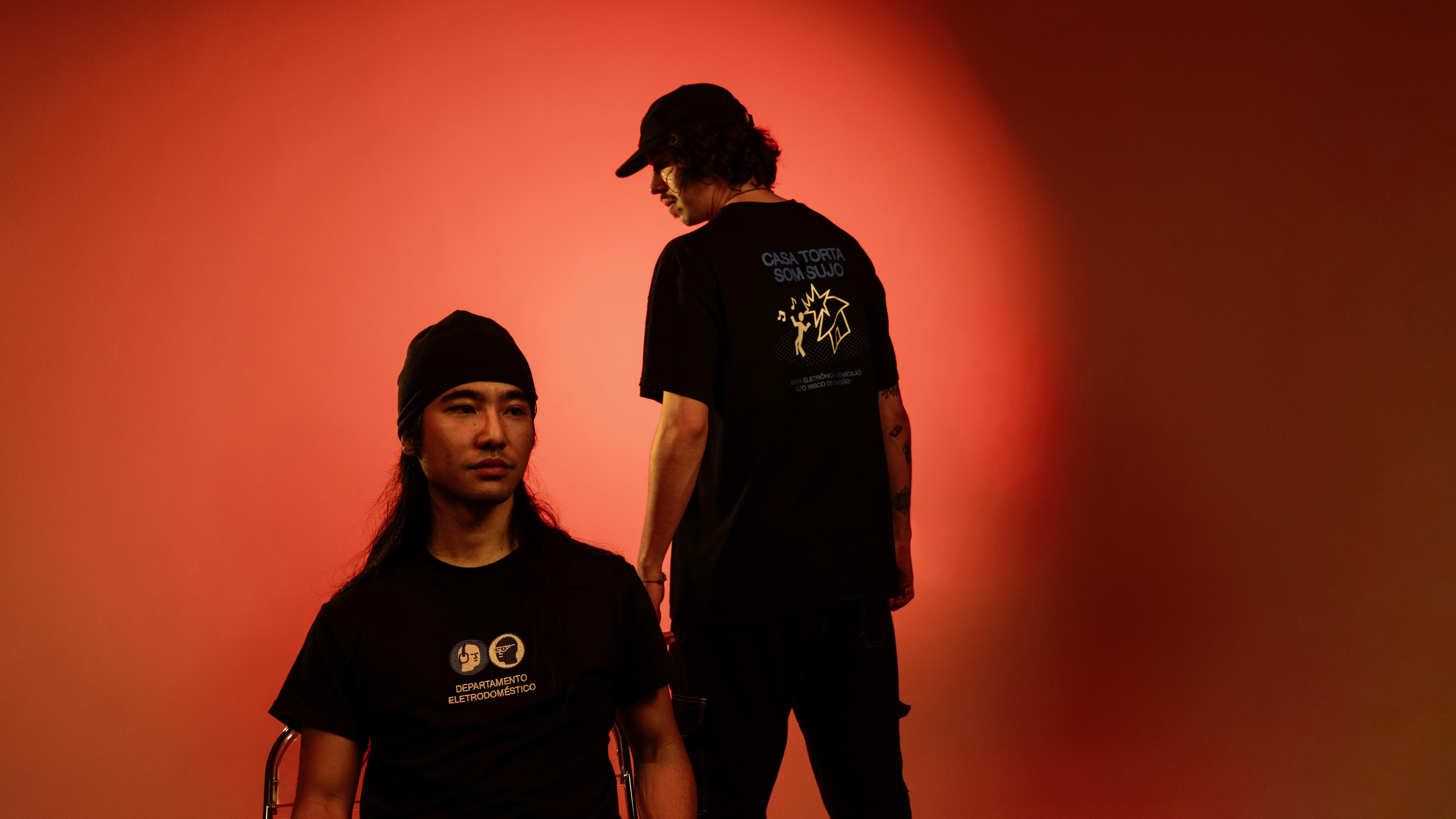 ingyenes Két modell kreatív stúdióportréja fekete pólóban, piros háttérvilágítással. Stockfotó