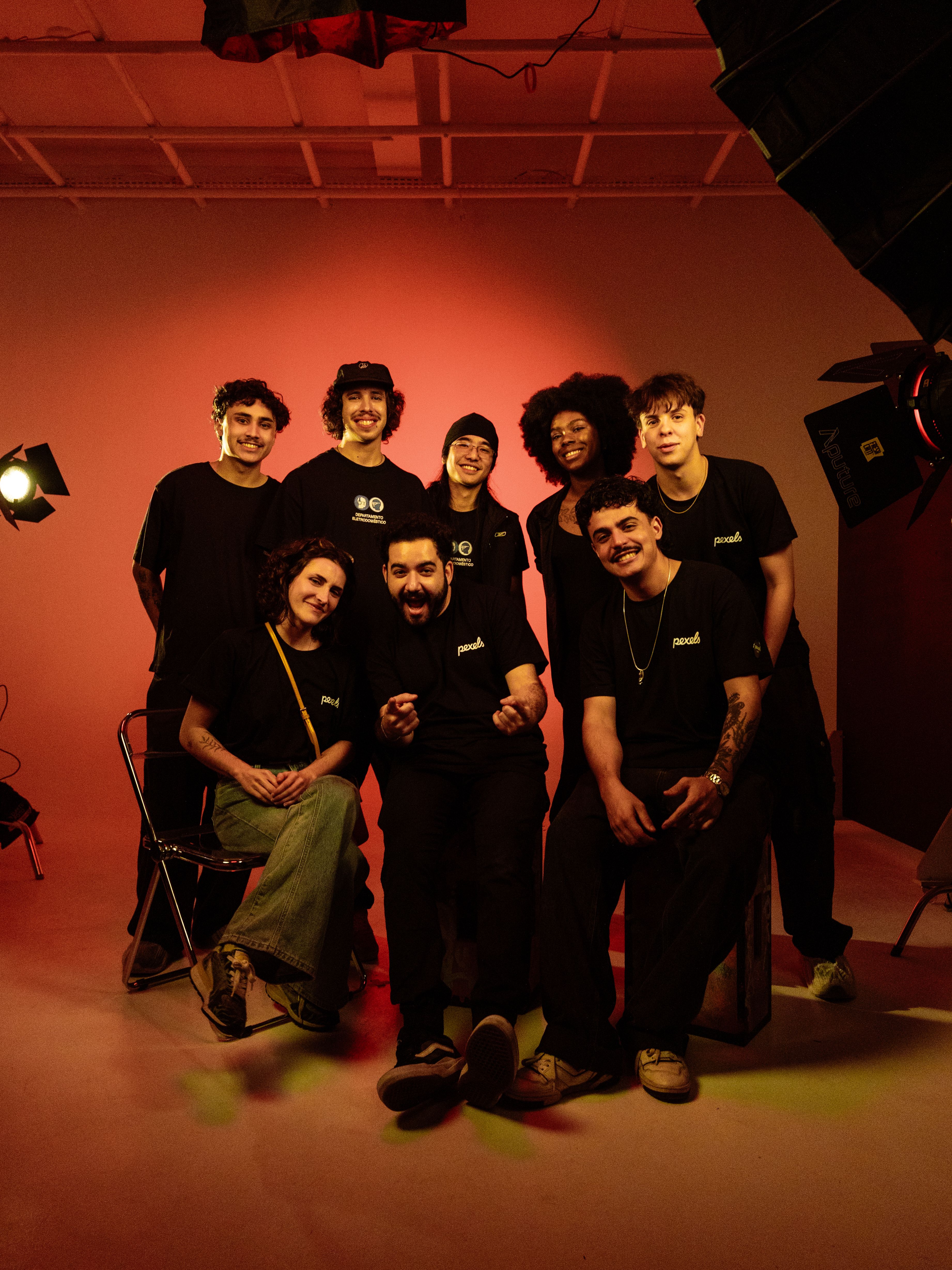 Portrait of a diverse group of young adults posing together in a studio setting with warm lighting.