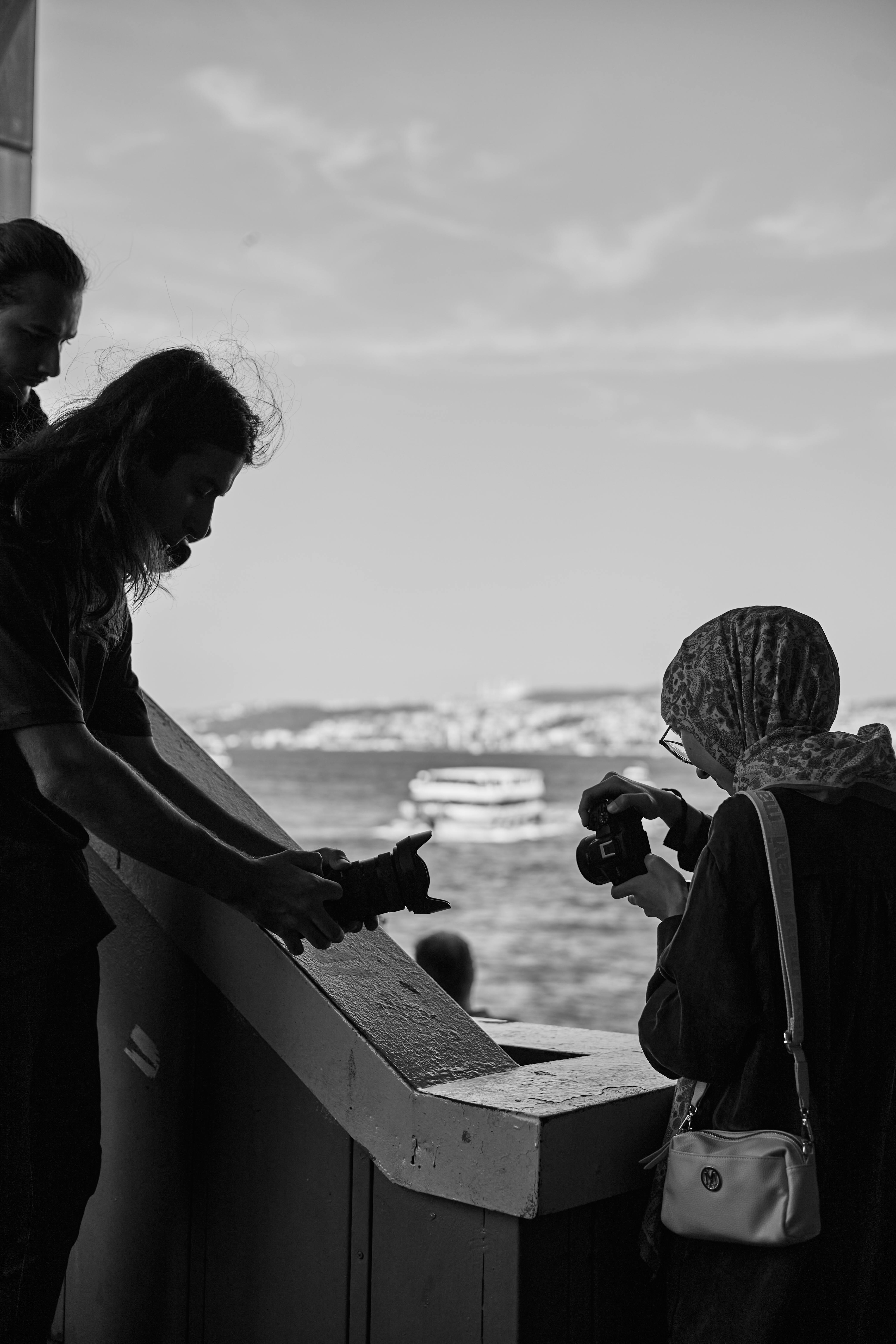 Three people sharing photography techniques with the Bosphorus backdrop in Istanbul.