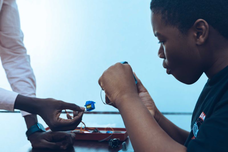 Two students work on a hands-on project, connecting components in a tech class