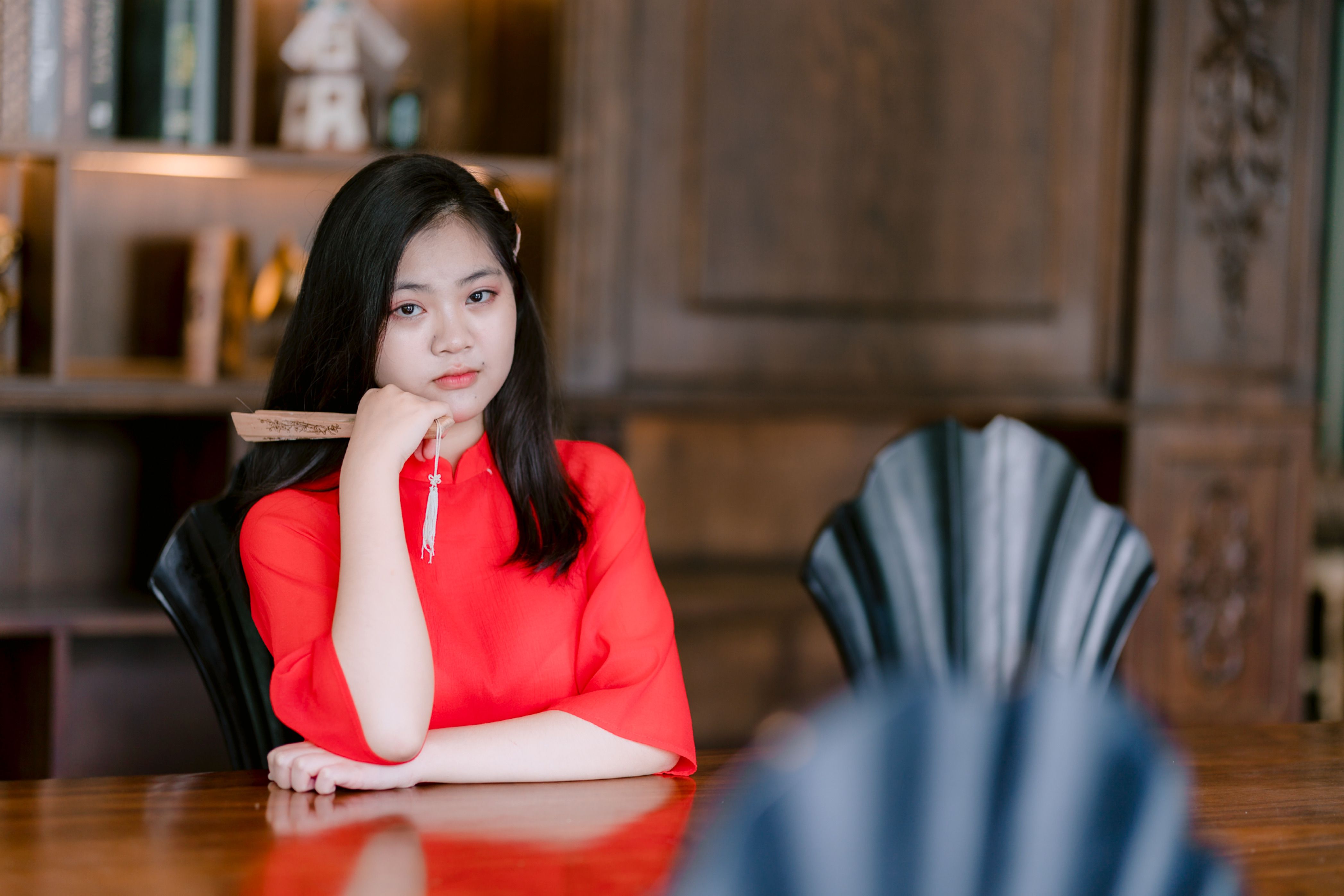 Young Woman in Red Dress Sitting at Wooden Table · Free Stock Photo