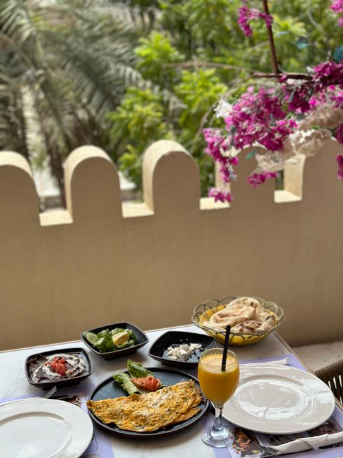 Free Delightful outdoor breakfast setup with omelette, sides, and fresh juice under blooming flowers. Stock Photo