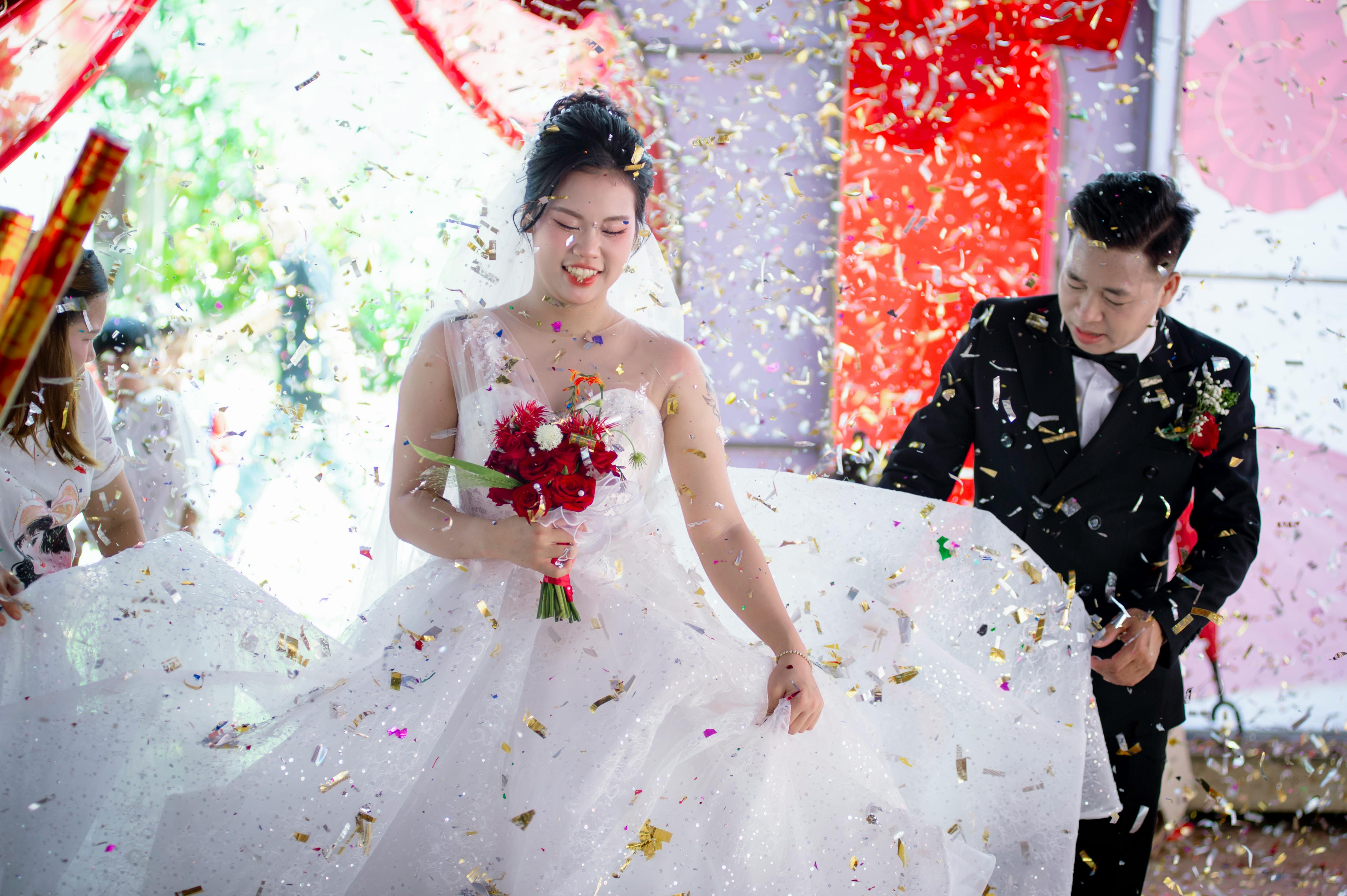 Gratis Vibrante escena de boda en Vietnam con novios celebrando en medio de una colorida lluvia de confeti. Foto de stock
