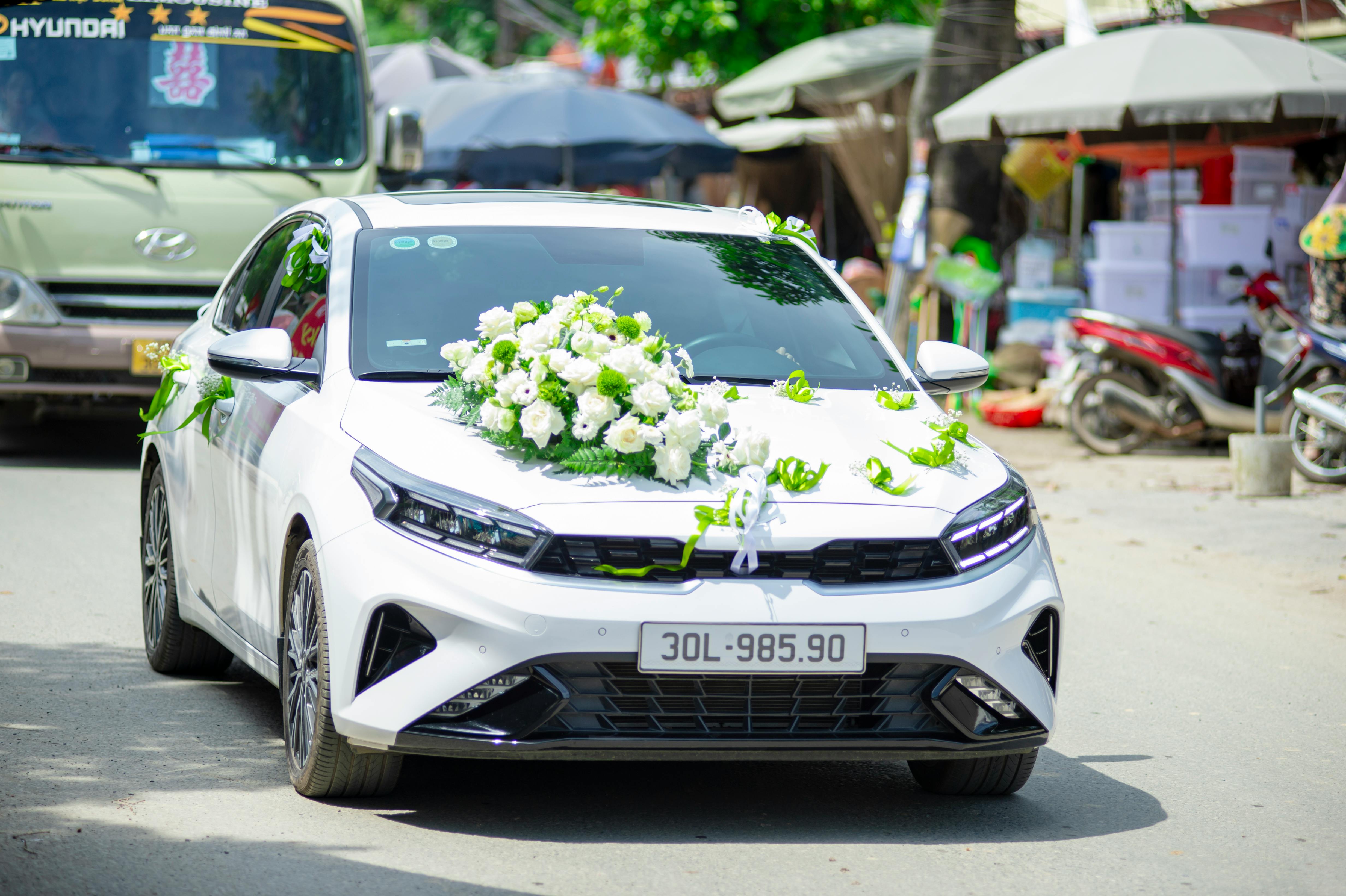 common:alt.prefix Un coche de bodas bellamente decorado y adornado con flores blancas, capturado en las calles de Vietnam. common:alt.postfix