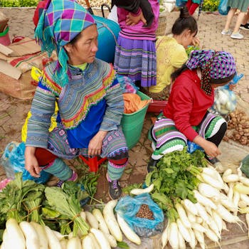 Capture of women in vibrant traditional attire selling produce at a Lào Cai market.