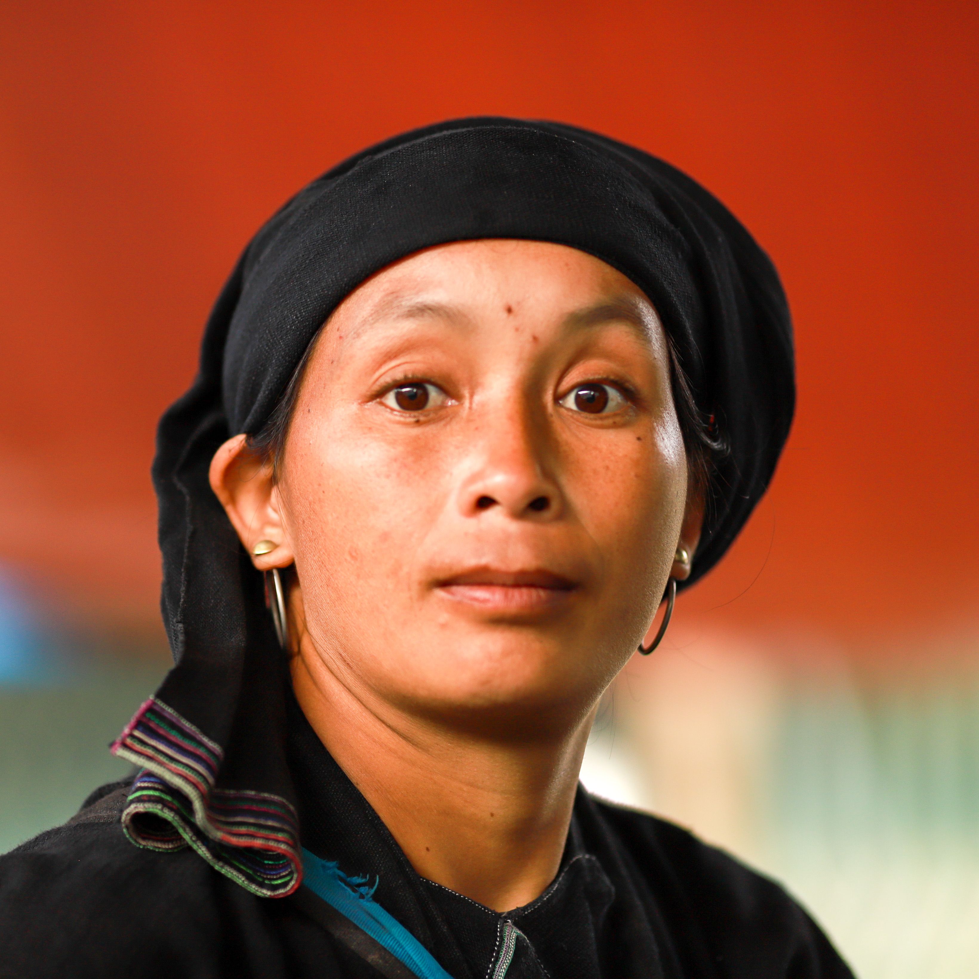 Portrait of a woman in traditional ethnic attire at the outdoor Lào Cai Market, capturing cultural essence.