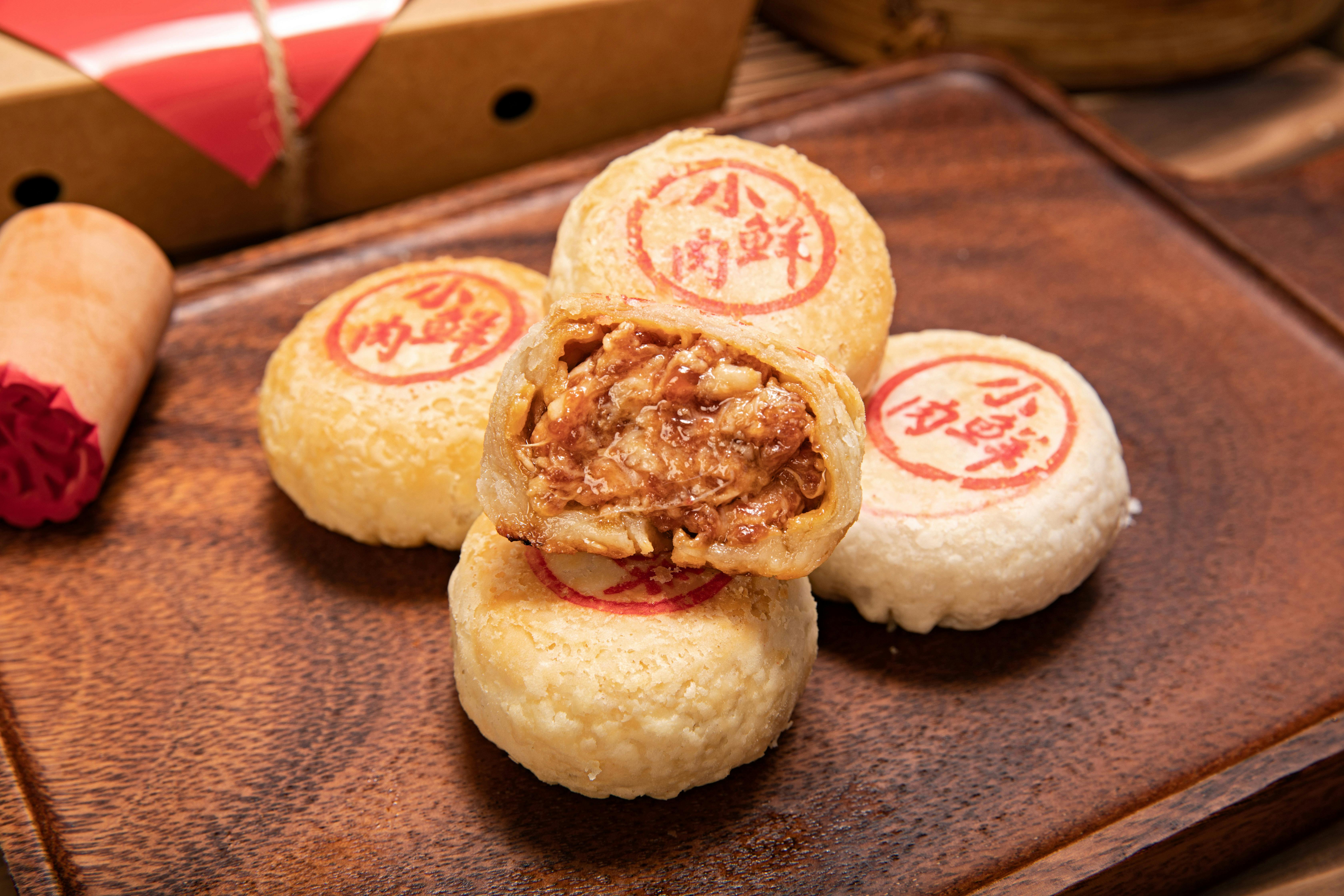 Close-up of traditional Chinese mooncakes with a meat filling displayed on a wooden plate.