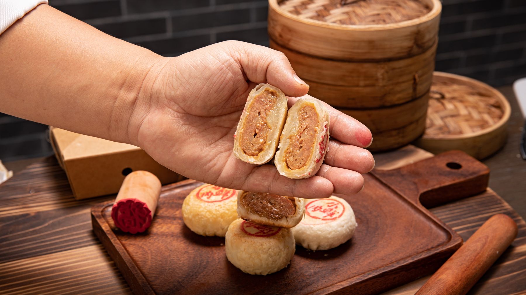 Primo piano di mooncake cinesi tradizionali con una mano che mostra il ripieno interno.
