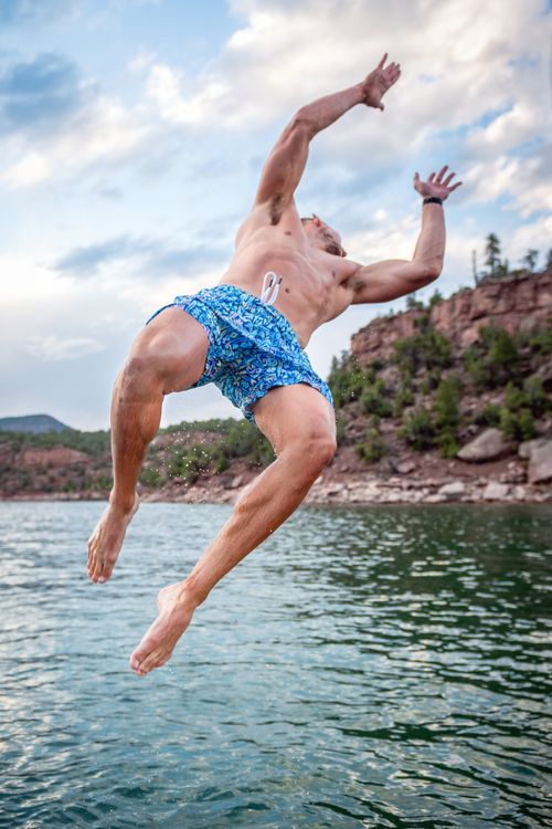 Free Athletic man diving into lake with clear sky and scenic hills in the background. Stock Photo