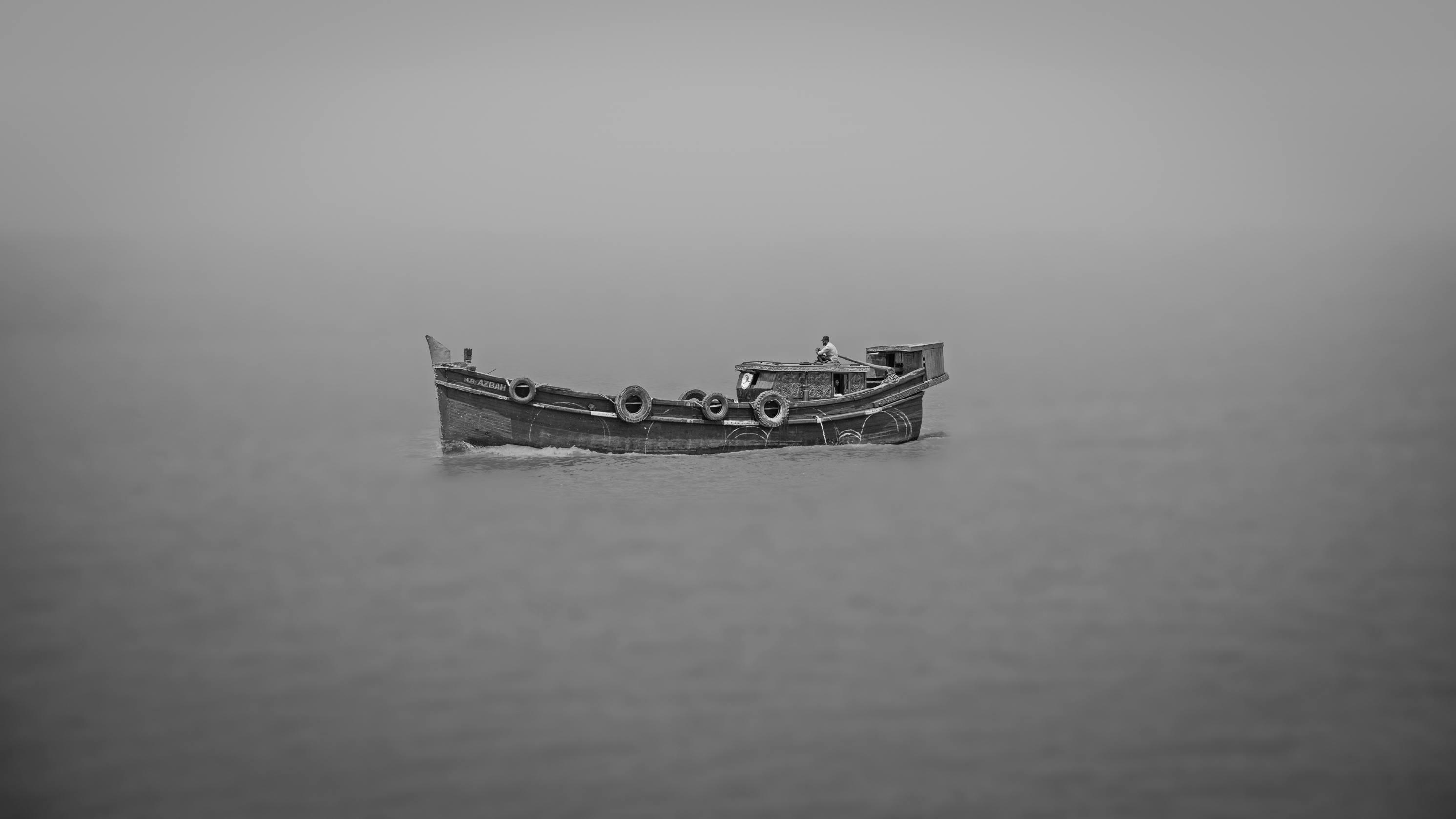 Gratis Una barca da pesca solitaria galleggia nelle acque nebbiose, creando un'atmosfera mistica. Foto a disposizione