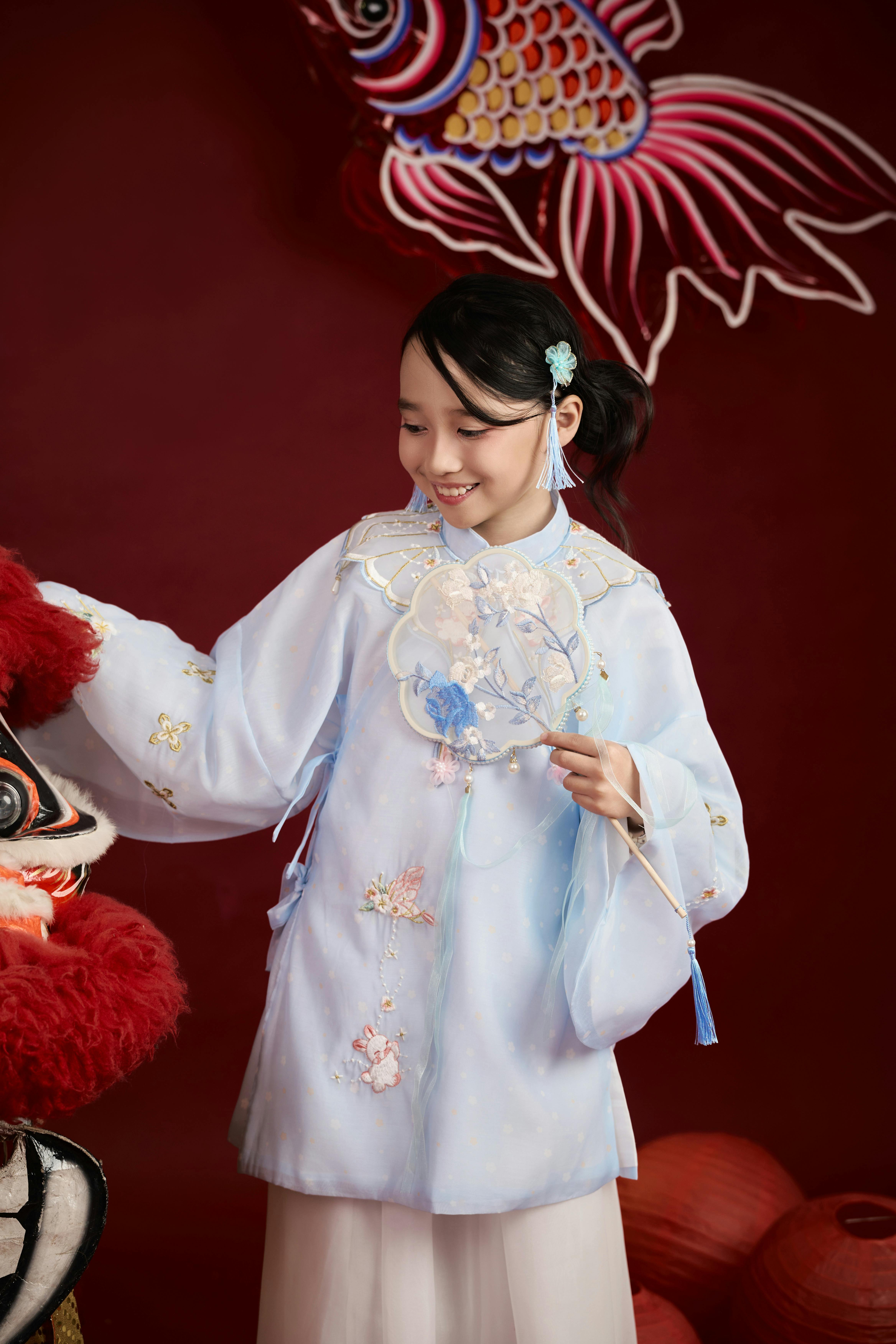 Gratis Una giovane ragazza in abito tradizionale festivo ammira un costume da danza del leone, che cattura l'essenza della cultura vietnamita. Foto a disposizione