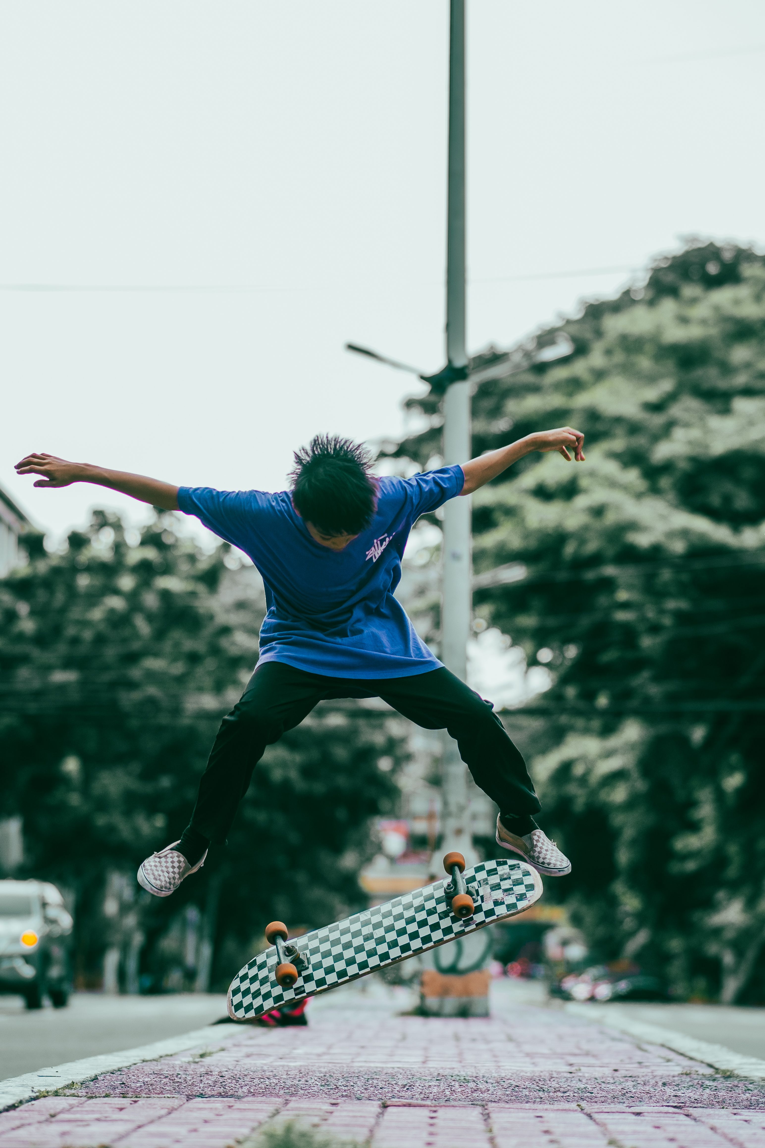 Dynamic shot of a skateboarder in mid-air performing tricks on an urban street.. dynamic, shot, skateboarder