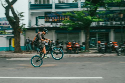 Free A young adult performing a wheelie on a BMX bike in an urban street scene. Stock Photo